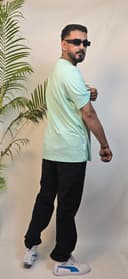 Man standing next to a white cylindrical planter with green plants on a white floor.