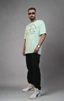 Person standing next to a plant on a white floor with a white wall background