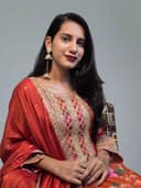 Woman wearing a traditional embroidered outfit with a neutral background