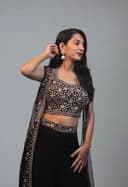 Woman in a black and white traditional outfit with plants in the foreground