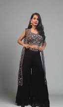 Woman in a black and white traditional outfit with plants in the foreground