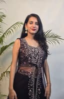 Woman in a black and white traditional outfit with plants in the foreground