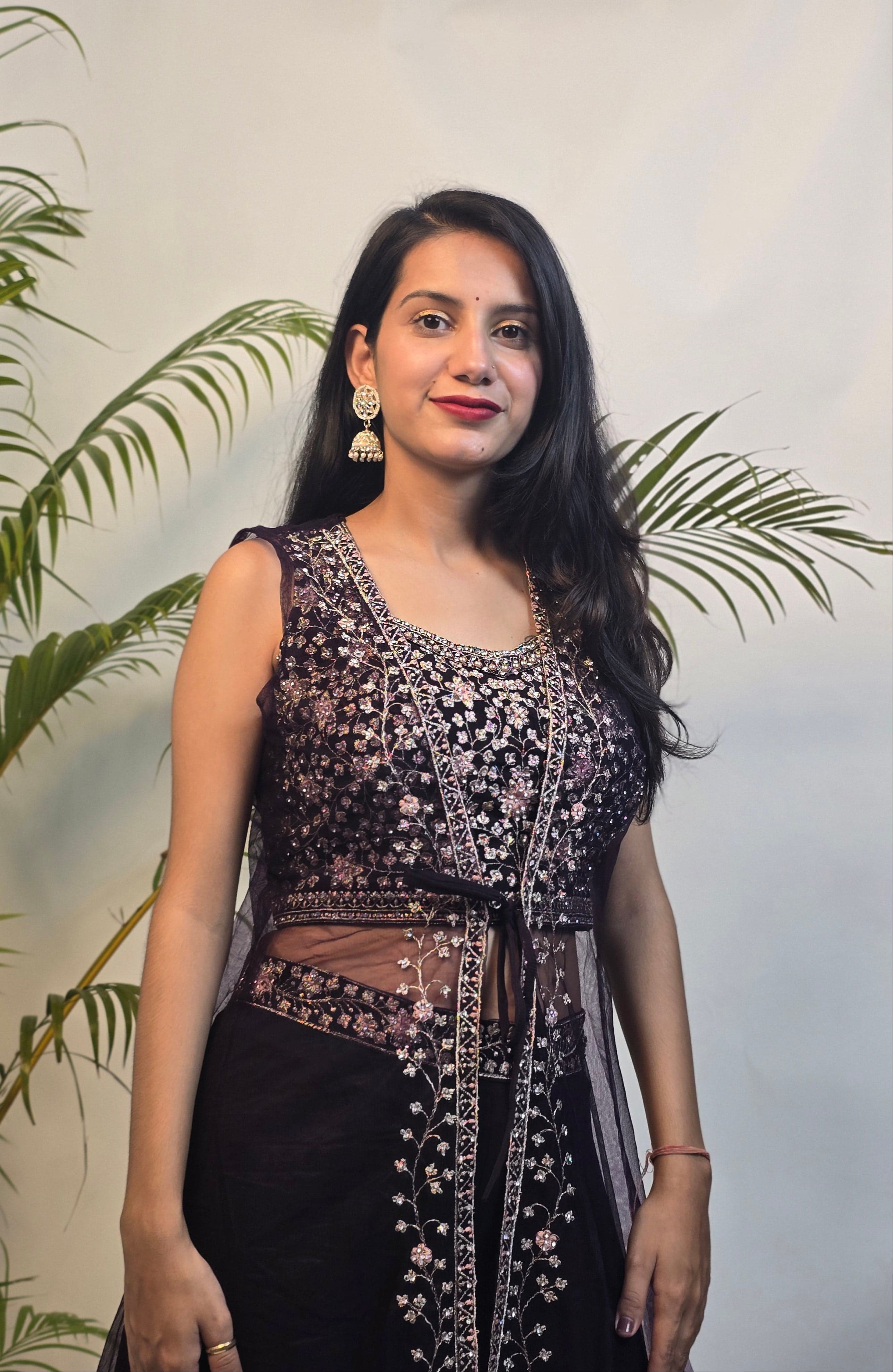 Woman in a black and white traditional outfit with plants in the foreground
