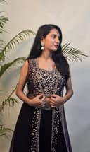 Woman in a black and white traditional outfit with plants in the foreground