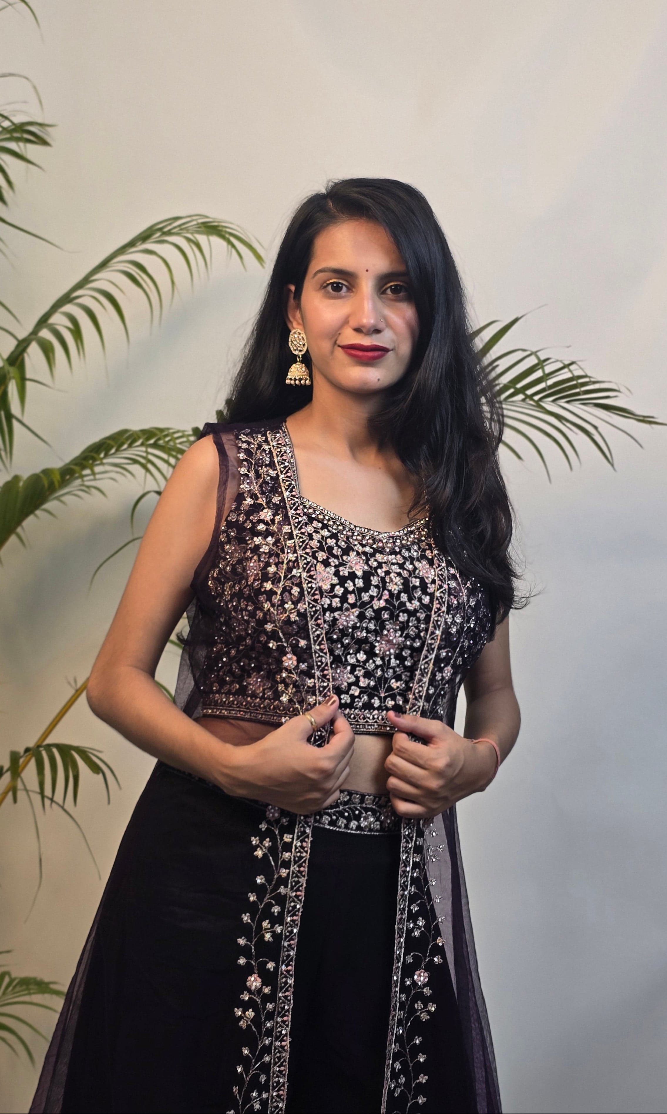 Woman in a black and white traditional outfit with plants in the foreground