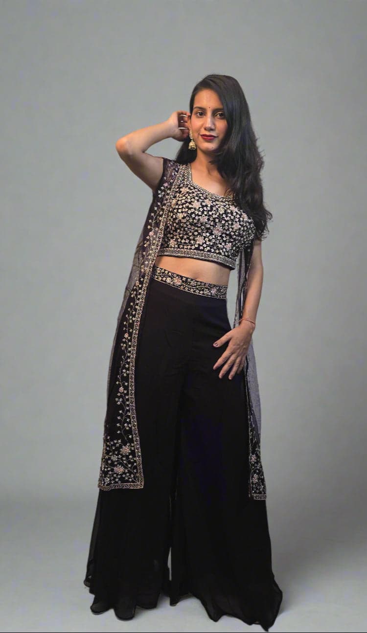 Woman in a black and white traditional outfit with plants in the foreground