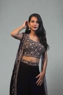 Woman in a black and white traditional outfit with plants in the foreground