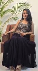 Woman in a black and white traditional outfit with plants in the foreground