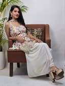 Woman sitting on a chair with a floral dress, holding a pillow.