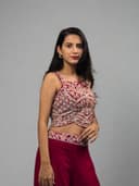 Woman in a red and white traditional outfit lying on a reflective surface with green leaves.