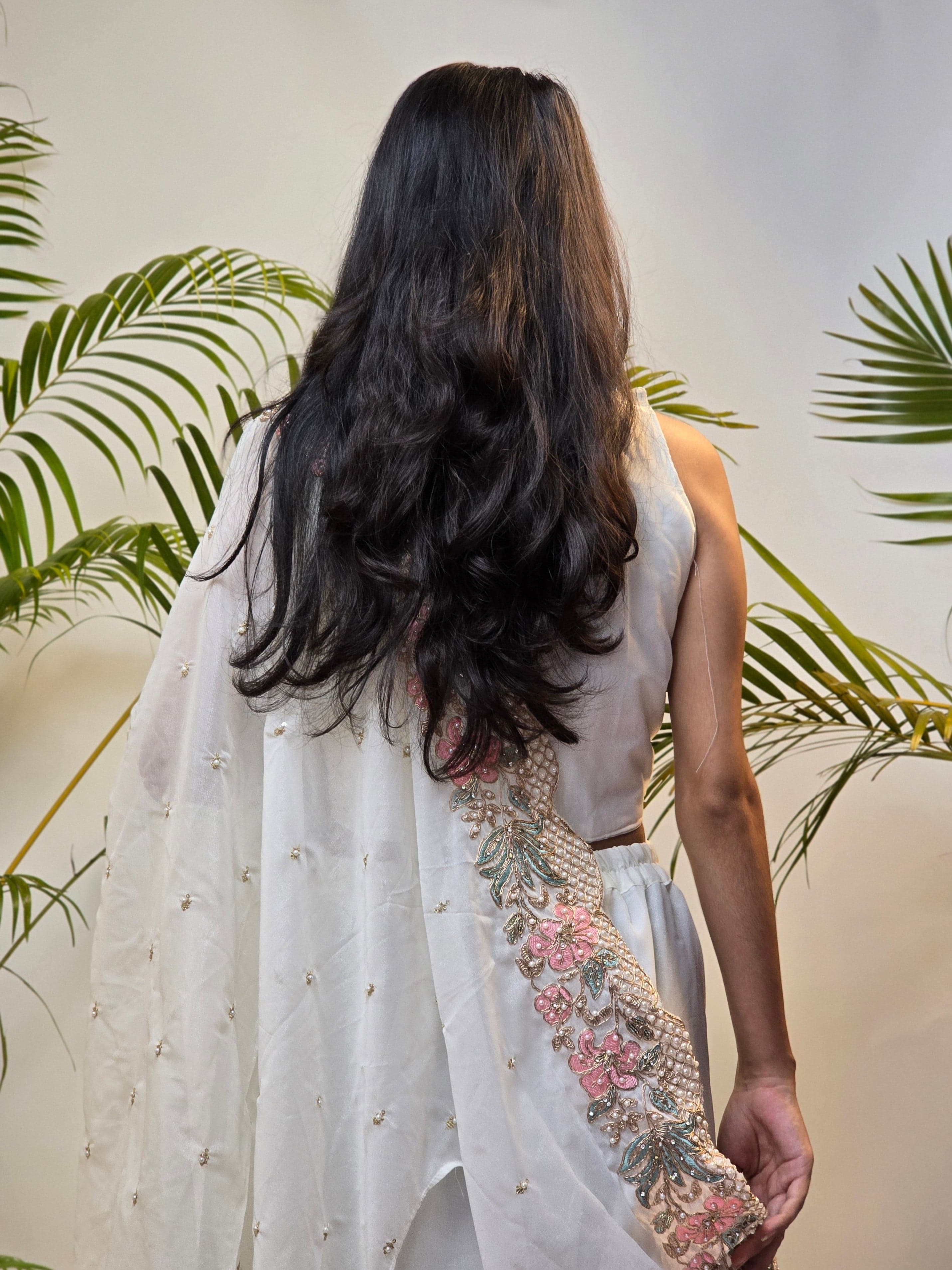 Person lying on a white surface with floral and leaf patterns, surrounded by green leaves.