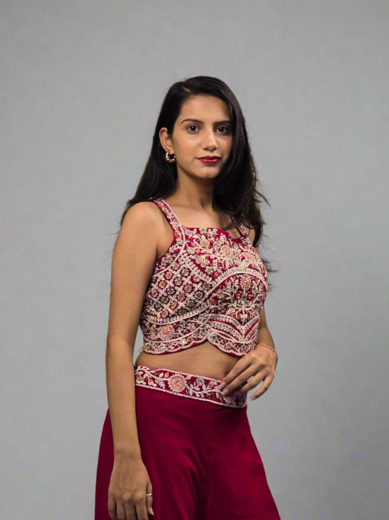 Woman in a red and white traditional outfit lying on a reflective surface with green leaves.